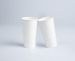 Two 20 oz paper cups stacked on top of each other, angled, end to end, on a white background.