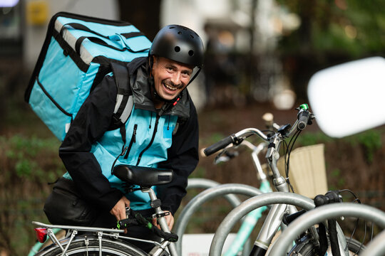 Smiling delivery man securing his bike after delivering food