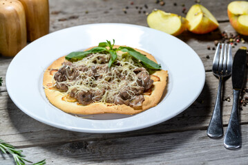 flatbread with meat, cheese and herbs on a white plate