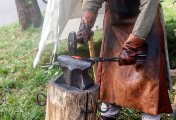 Man is forging a piece of metal with a hammer and an anvil