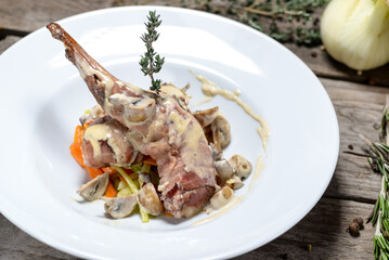 fried rabbit leg in creamy sauce on a white plate macro