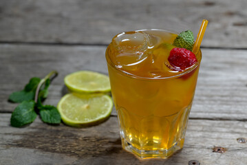 cocktail with ice decorated with raspberries on a wooden background with mint