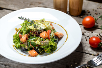fresh salad with tomatoes and salmon in a white plate