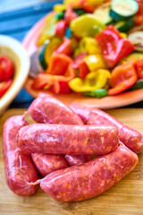 Raw Sausages on Wooden Board and Vegetable Platter