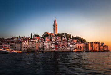 Fototapeta premium Rovinj, Croatia - Sunset view of beautiful Old Town of Rovinj with the tower of Saint Euphemia church in Adriatic sea coast. Clear blue sky, golden sunset colours