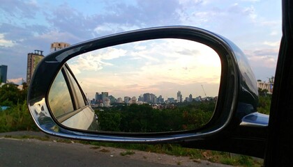 Obraz premium Cityscape Reflected in Car Mirror at Sunset