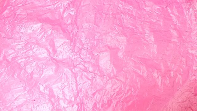 Neon Pink crumpled plastic bag texture background rotating. Real High-Density Polyethylene shopping bag. HDPE shopper texture