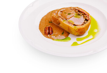 Elegant pork Wellington with mushroom and nut filling, served with creamy pecan sauce and green herb oil on white plate