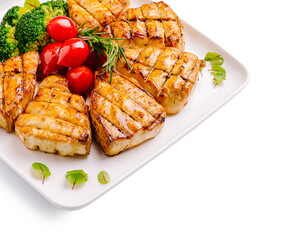 Grilled fish with vegetables served on a white plate at a dining table