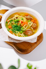 Hearty soup with meatballs and vegetables served in a white bowl