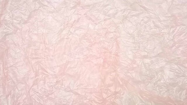 Pink crumpled plastic bag texture background rotating. Real Low-Density Polyethylene shopping bag. LDPE shopper texture,