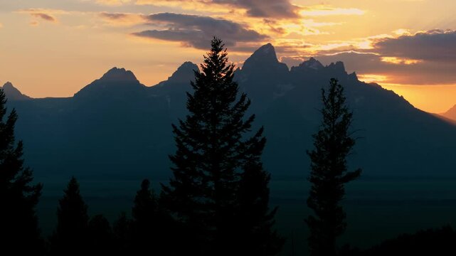 Sunset over Tetons, Wyoming, trees visible, peaceful outdoor scene