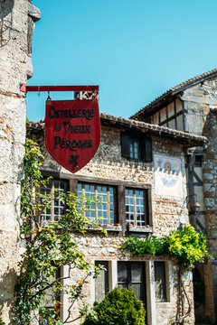 Rustic medieval inn sign of Hostellerie du Vieux Perouges against stone houses with timber frames and sundial details in the historic village of Perouges France August 19 2025