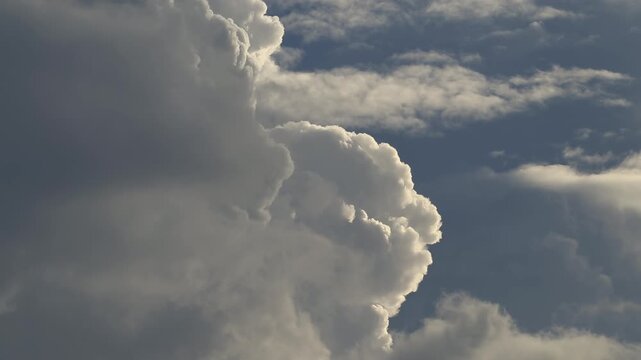 A dramatic time-lapse or slow motion video of powerful storm clouds backlit by the sun, creating a beautiful silver lining effect on their edges.
