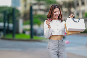 Fototapeta premium Eco-Conscious Asian Woman Holding Reusable Shopping Bags Outdoors