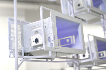 Powder coating workshop with microwave oven casings on an overhead conveyor system