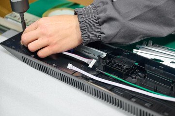 Person assembling electronic device components on a workbench during daytime in a well-lit workshop