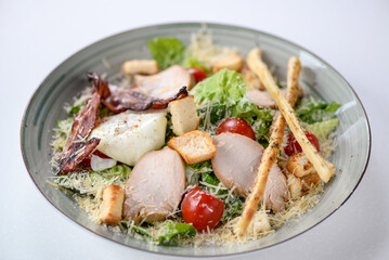 Caesar salad with bacon and grissini on a plate on a background