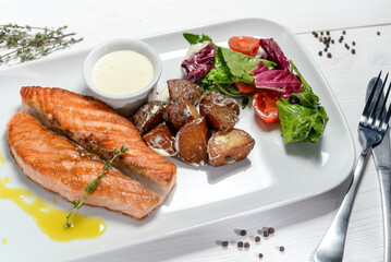 Grilled salmon steak on a plate with salad on a white background