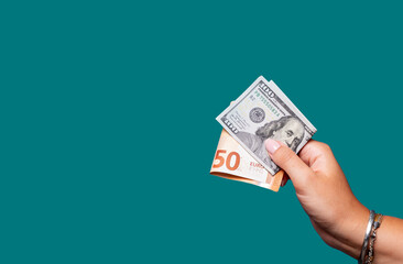Hand holding dollar and euro bills over green background 