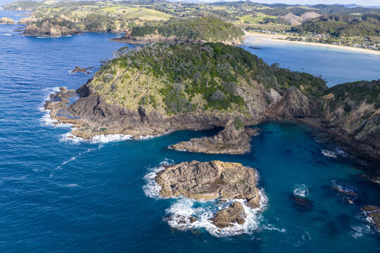 Aerial view of rocky outcrops meet the turquoise sea near the green peninsula of Matapouri, where land and water create a stunning contrast, Matapouri, Te Tai-tokerau, New Zealand.