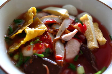 Close up Yentafo or Thai pink noodles soup in bowl topping with ingredient.