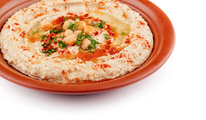Hummus topped with chickpeas, olive oil, parsley and paprika is served on a plate