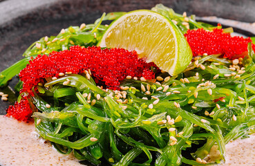 Fresh seaweed salad with tobiko garnish and lime