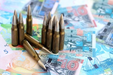 Kuwaiti dinar currency money bills and rifle bullets. The concept of warfare and gun selling