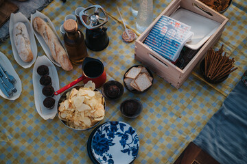 A table set outdoors displaying chips, muffins, baguettes, pretzels, and other snacks, suggesting an enjoyable gathering or party.