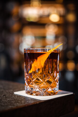 Negroni cocktail on the bar, bo. equal parts gin, vermouth rosso, and Campari, garnished with an orange peel.