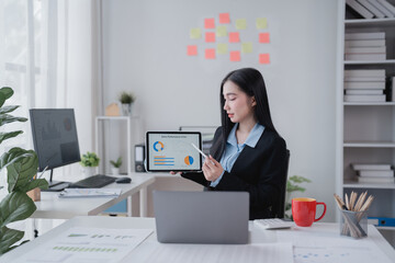 Young businesswoman presenting sales performance chart on digital tablet during online meeting via video conference application in bright modern office, working with financial charts and graphs