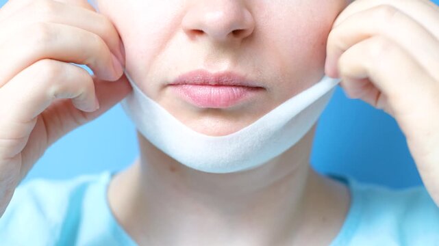 Portrait of a young woman with a mask for a double chin front view close-up on blue background.
