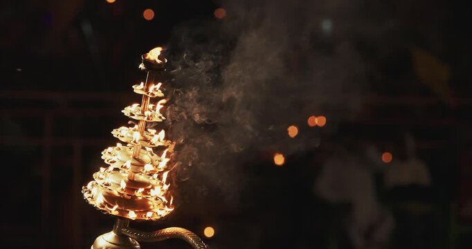 Varanasi, India. Man makes movements with a candle holder with lit candles on the Ganga Maha Aarti ceremony begins. Brahman priest wearing red and yellow dress doing traditional ganga aarti at ghat