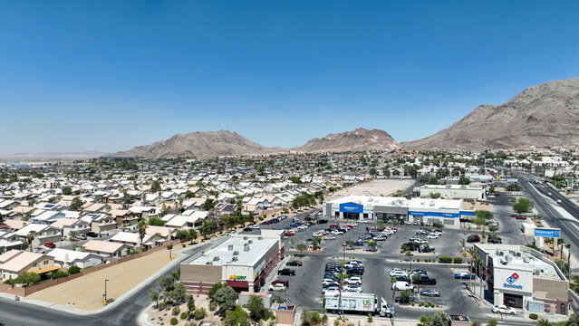 Aerial view of commercial buildings and residential houses nestled beneath the stark mountain range under a clear sky, Las Vegas, Nevada, United States.