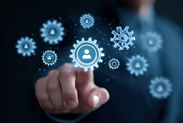 A blurry hand reaches towards glowing blue gears with human icons against a dark background, symbolizing connectivity and teamwork in a modern context