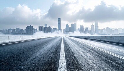 Fototapeta premium Road stretches towards the city skyline shrouded in mist and clouds on a cold, overcast day, creating a sense of mystery and urban isolation.