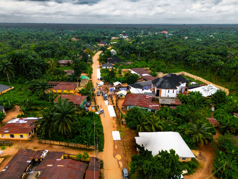 Aerial view of a vibrant path cutting through lush green foliage, dotted with buildings, under a cloudy sky, Amaolu Community, Orlu, Imo, Nigeria.