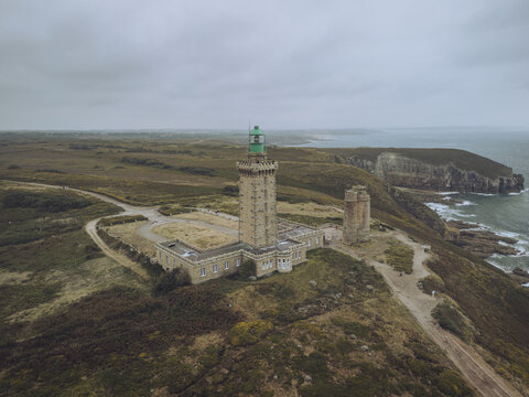 Aerial view of Phare du Cap Fr&Atilde;&copy;hel lighthouse stands tall against the rugged coastline, where the emerald sea meets the ochre cliffs, Pl&Atilde;&copy;venon, Bretagne, France.
