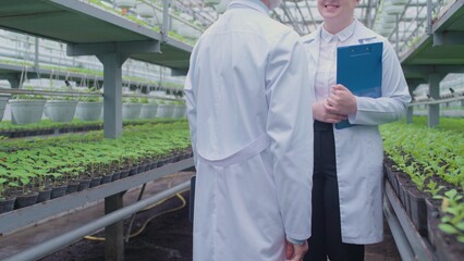 Biology specialists meeting in glasshouse, discussing agricultural business