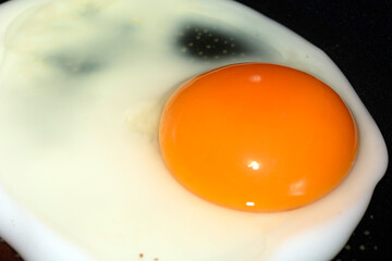 Close up of a fried egg in a pan being cooked