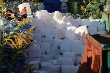 Pile of white plastic canisters at a waste collection site — symbol of plastic pollution and the urgent need for recycling