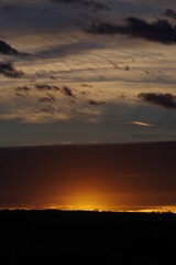 The sky is dark and cloudy with a bright orange sun in the background