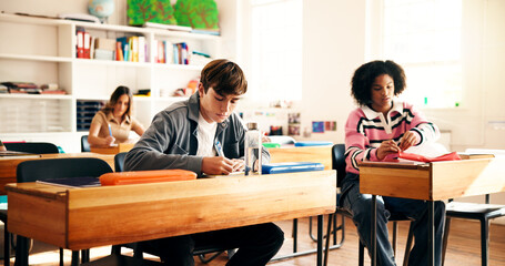 People, teenager and writing with books in classroom for education, learning or development. Boy, students and studying with textbooks in class for knowledge, assessment or exam in high school