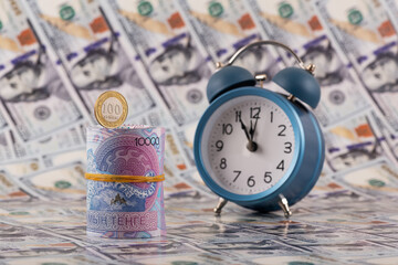 Banknotes of 10,000 Kazakhstani tenge and 100 tenge coin against the background of 100 US dollar bills