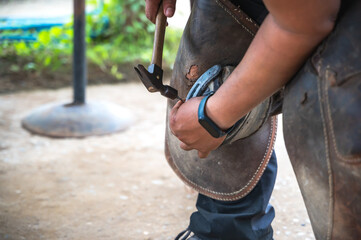 Close up unknown farrier nailing horseshoe in stable