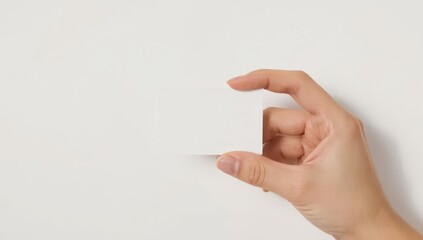 Obraz premium A blank rectangular card held by a hand against a plain white background.