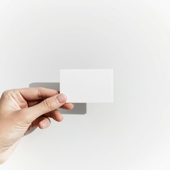 Obraz premium A hand holds a blank business card against a plain white background, showcasing a simple yet elegant design.