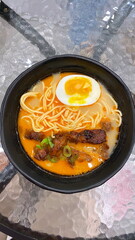 Authentic Japanese ramen bowl with creamy spicy broth, chewy noodles, soft boiled egg, grilled pork slices, and fresh green onions, traditional Japanese food popular in Asian cuisine