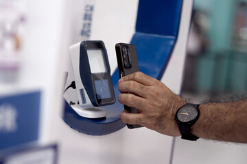 close up of an adult man's hand making a non-cash transaction by paying using his gadget